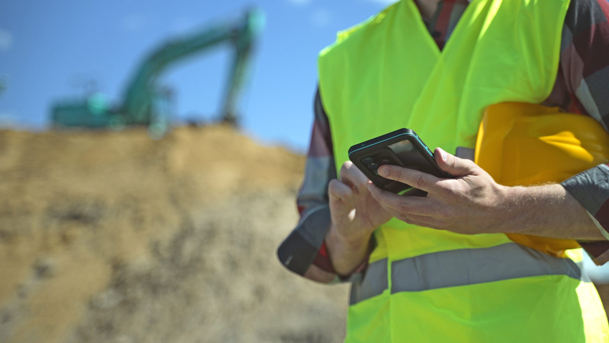 Builder with hard hat and high vis jacket using smartphone. Close-up. | OHIO811 Builder with hard hat and high vis jacket using smartphone. Close-up.