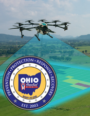 Six drones flying in formation over a grassy field, with a blue-and-gold circular insignia in the lower-left.