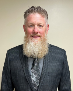 DANIEL BECKETT | OHIO811 Portrait of a man with a long gray beard wearing a dark checkered suit and striped gray tie.