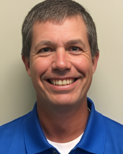 JAMES MANDERA | OHIO811 Smiling man with short gray hair wearing a blue polo shirt, facing the camera against a light background, head and shoulders.