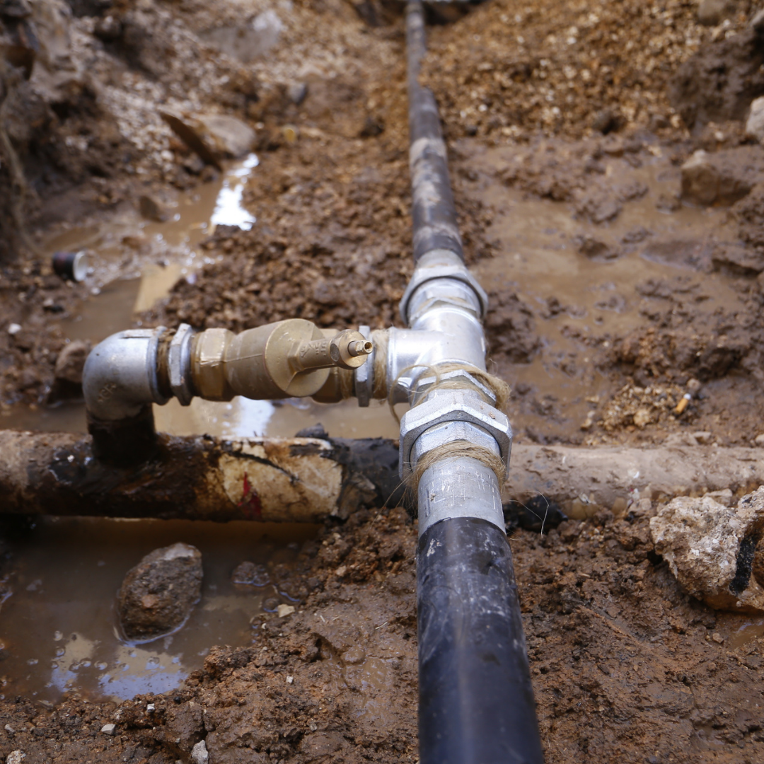 underground lines 1 | OHIO811 Metal pipe system with a brass valve in a muddy construction trench, connected by unions and fittings.