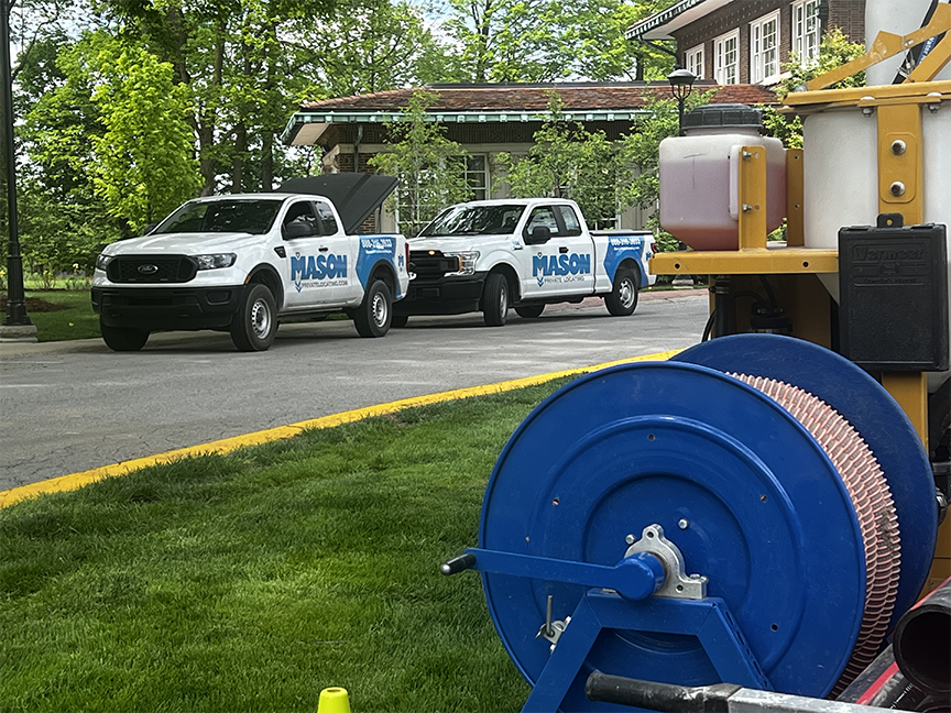 IMG_7229 small | OHIO811 Two Mason Public Works pickup trucks parked in a lot, with a large blue hose reel and utility equipment in the foreground.